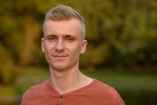 Portrait of young man with blond hair at the park outdoors