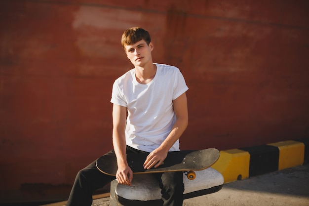 Portrait of young man with brown hair with skateboard