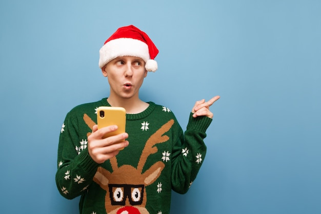 portrait young man with Christmas hat holding phone