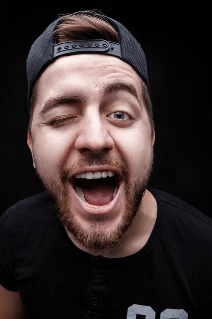 Photo portrait of young man with dark hair in shirt fooling around on black background rapper