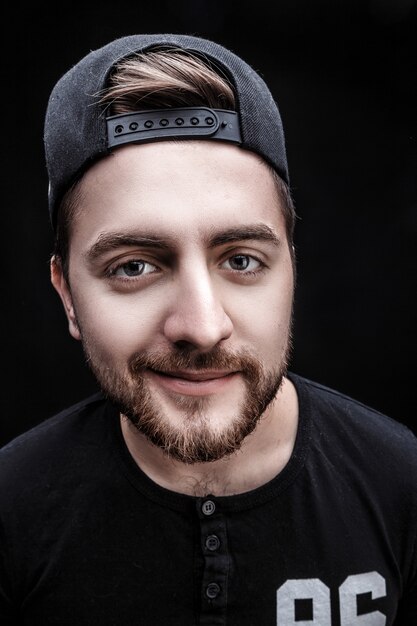 Portrait of young man with dark hair in shirt fooling around on black background rapper