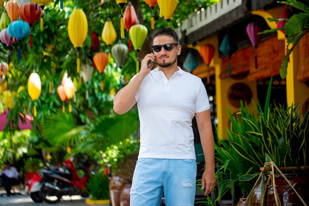 Portrait of a young man with glasses walking outdoors with a mobile phone . A man with a phone. A happy person is talking on the phone.