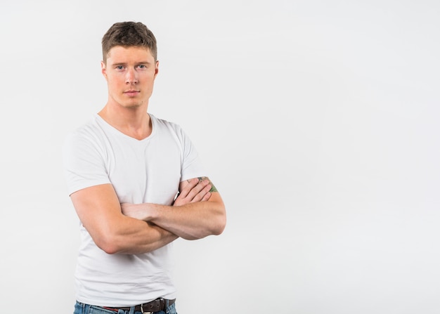 Portrait of a young man with his arm crossed looking to camera against white background