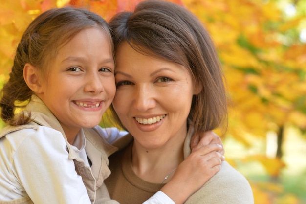 Portrait of young mother and daughter hugging in autumn park