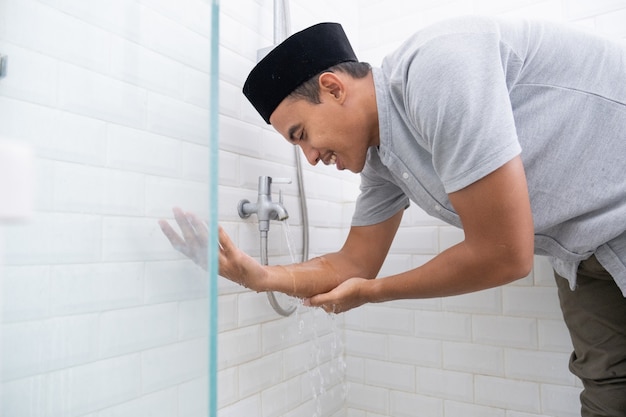 Portrait of young Muslim man perform ablution (wudhu) before prayer at home