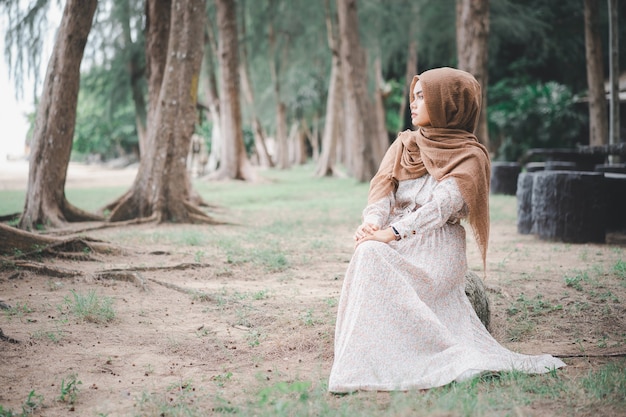 Portrait of young muslim woman brown hijab over blurred the pine forest