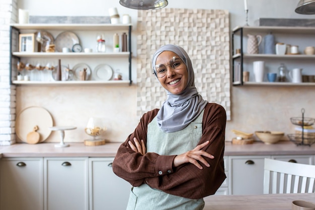 Portrait of young muslim woman food blogger coach chef in hijab standing at home in kitchen in apron