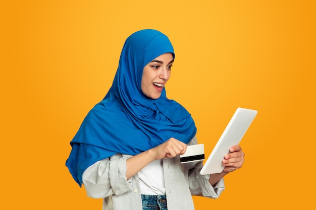 Portrait of young muslim woman isolated on yellow studio background