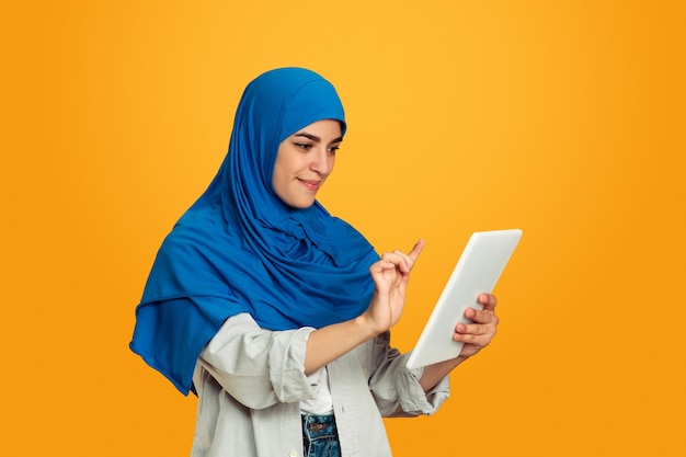 Portrait of young muslim woman on yellow wall