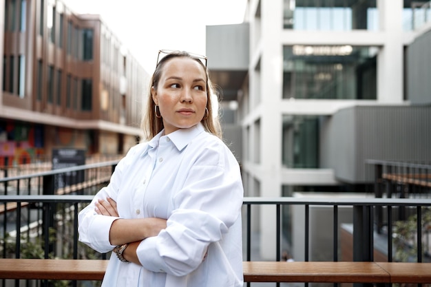 Portrait of young office woman standing on balcony enjoying city view