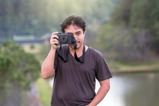 Portrait of young photographer over the forest with lake background