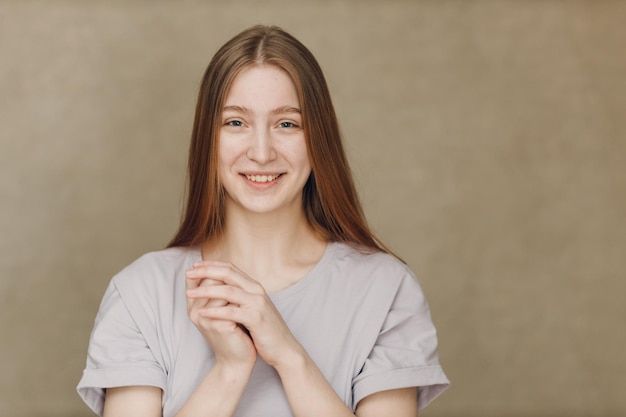 Portrait of young pretty smiling woman looking at camera against beige background