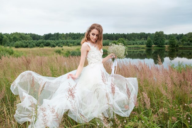 Portrait of young pretty woman (bride) in white wedding dress outdoors, make up and hairstyle