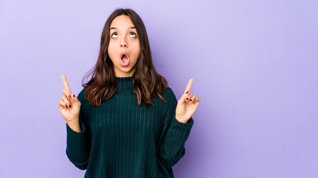 Portrait of a young pretty woman pointing up