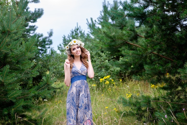 Portrait of young pretty woman with circlet of camomile flowers on head, outdoors, make up and hairstyle