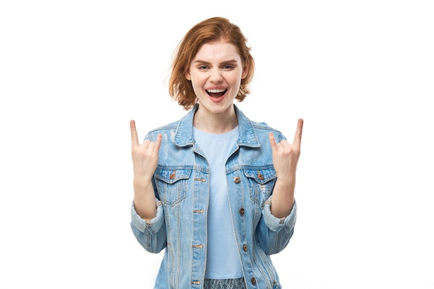 Portrait of young redhead woman showing rock and roll gesture with fingers isolated on white background