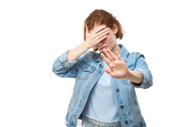 Portrait of young redhead woman showing stop sign with hand isolated on white background