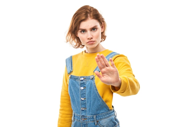 Portrait of young redhead woman showing stop sign with hand isolated on white background