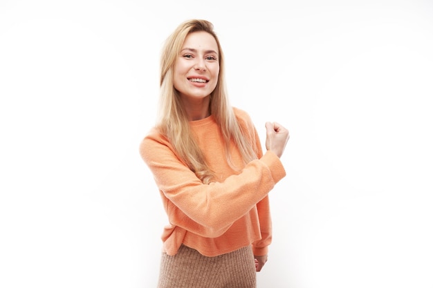 Portrait of young sexy blond woman showing biceps demonstrating girl power isolated on white background