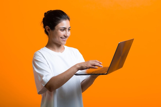 Portrait of young smiling adult indian woman working with laptop computer