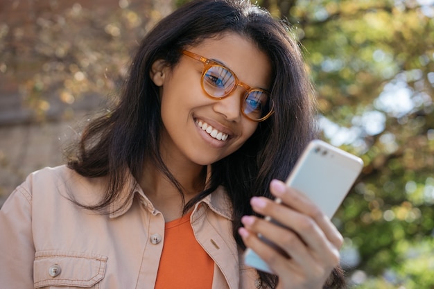 Portrait of young smiling African American woman using mobile phone, communication, chatting