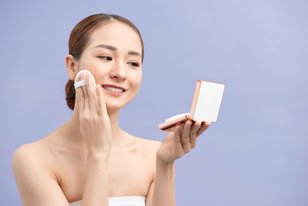 Portrait of young smiling Asian woman applying cushion foundation on her face