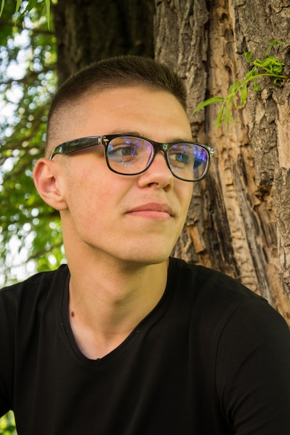 Portrait of young and smiling cute man with glasses in park