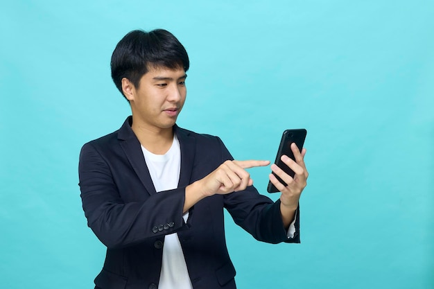 Portrait of a Young smiling handsome Asian man in a semiformal suit using a mobile phone