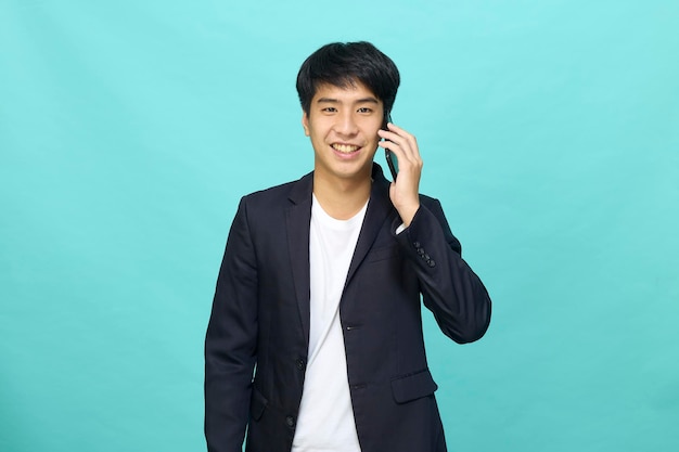 Portrait of a Young smiling handsome Asian man in a semiformal suit using a mobile phone