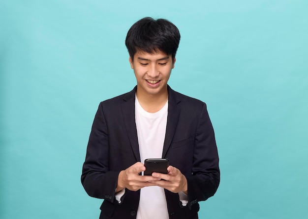 Portrait of a Young smiling handsome Asian man in a semiformal suit using a mobile phone