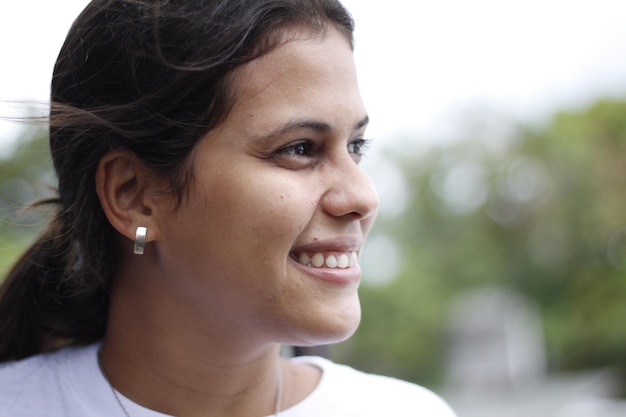 Portrait of young smiling latin woman face partially covered with flying hair standing