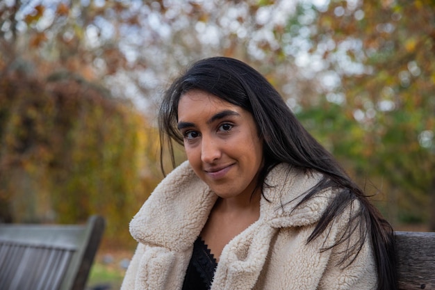 Portrait of a young smiling and longhaired indian girl in a London park