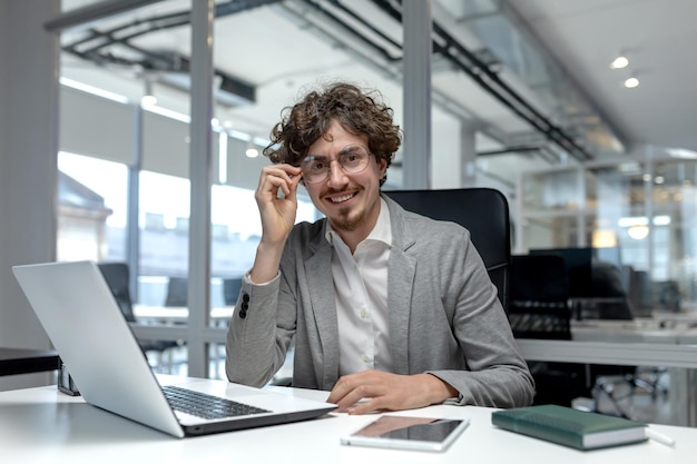 Portrait of a young smiling and successful young man sitting in the office at a desk and working on