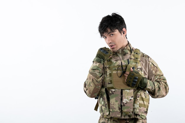 Portrait of young soldier in military uniform on white wall