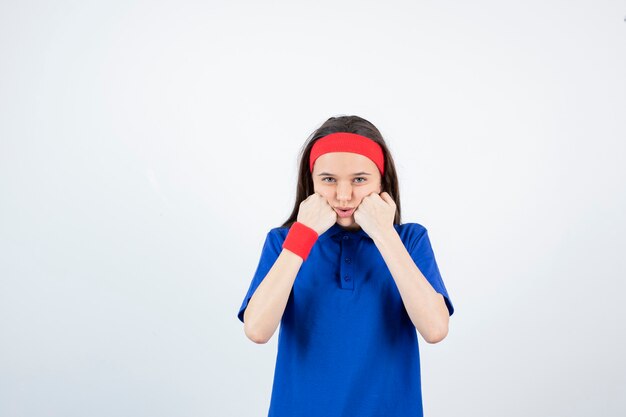 Portrait of a young sporty girl standing and posing on a white wall