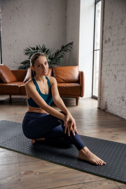 Portrait of young sporty woman practicing yoga and stretching body at home. High quality photo