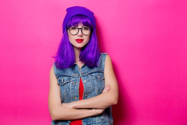 Portrait of young style hipster girl with purple hair on pink background