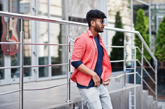 Portrait of young stylish indian man model pose in street in sunglasses.