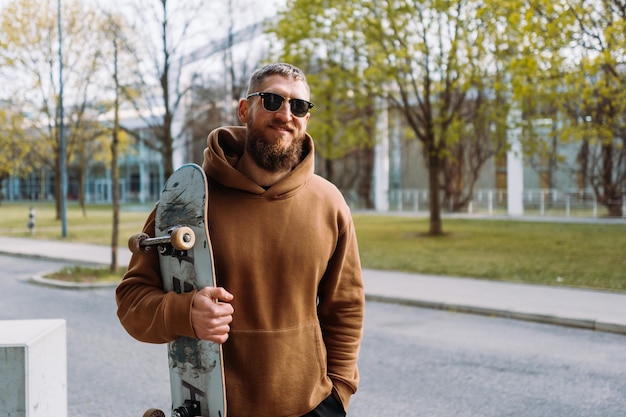 Portrait of a young stylish man holds a skateboard in his hand Copy space Best quality photo