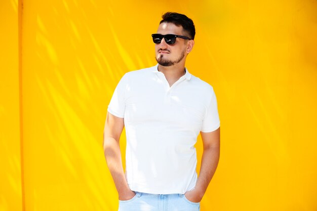 Portrait of a young stylish man with a beard in sunglasses and a white t-shirt