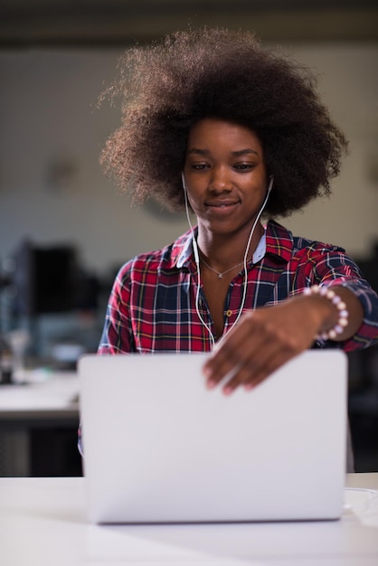 portrait of a young successful African American beautiful woman who enjoys spending a quality and joyful time while working in a large modern office