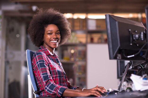 portrait of a young successful African American beautiful woman who enjoys spending a quality and joyful time while working in a large modern office