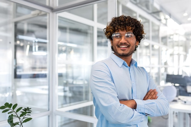 Portrait of young successful businessman inside modern office hispanic man satisfied smiling and