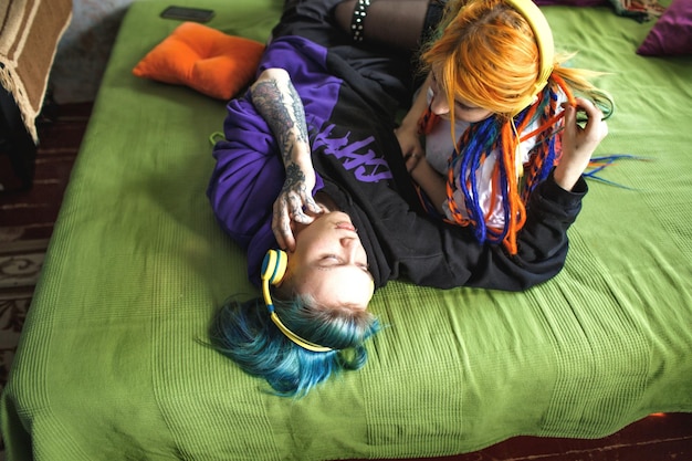 Portrait of a young tattooed punk couple of a girl and a guy with long dyed hair braided lying