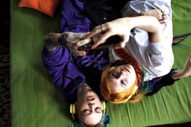 Portrait of a young tattooed punk couple of a girl and a guy with long dyed hair braided lying on