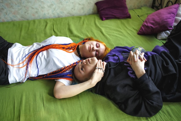 Portrait of a young tattooed punk couple of a girl and a guy with long dyed hair braided lying