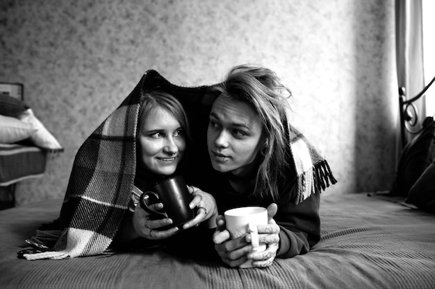 Portrait of a young tattooed punk couple of a girl and a guy with long dyed hair braided lying