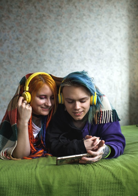 Portrait of a young tattooed punk couple of a girl and a guy with long dyed hair braided lying