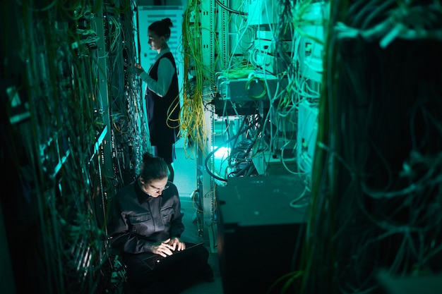 Portrait of young technician setting up computer network in server room, copy space