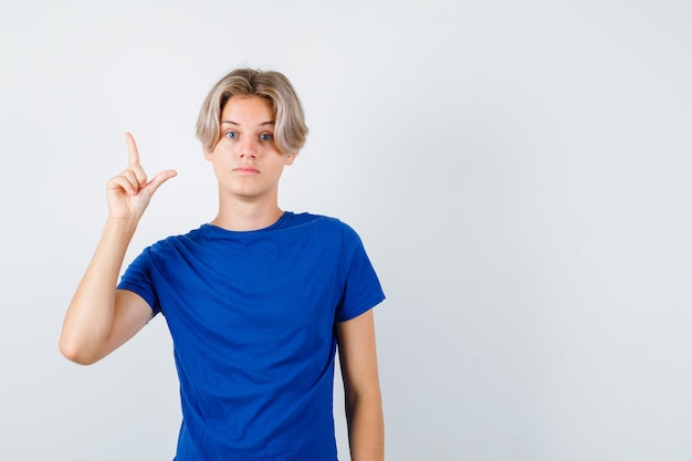 Portrait of young teen boy pointing up in blue t-shirt and looking smart front view